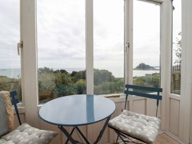A table and chairs in a conservatory with a sea view at Greeb Rocks Cottage Marazion