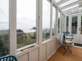 A conservatory with chairs and a view at Greeb Rocks Cottage Marazion