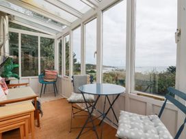 A conservatory with a table and chairs at Greeb Rocks Cottage in Marazion