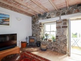 A living room with a wood stove and a television at Greeb Rocks Cottage in Marazion