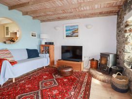 A living room with a sofa, TV, and fireplace at Greeb Rocks Cottage in Marazion