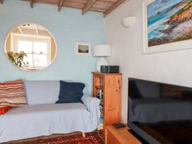 A living room with a sofa and bookshelf at Greeb Rocks Cottage Marazion