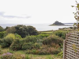 A view of a seaside landscape with a garden and a castle on an island at Greeb Rocks Cottage in Marazion
