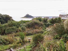 A garden with various plants and a view of the sea and castle at Greeb Rocks Cottage Marazion