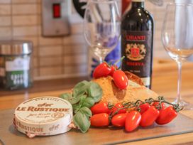 A cheese, tomatoes, bread, and wine in a kitchen at Haven House Whitby