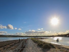 A beach scene with people walking along the shore at Hen Hafod in Talwrn near Llangefni