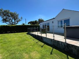 An outdoor area with a house and glass railing at Rhos Y Foel Cottage in Nefyn