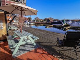 An outdoor seating area by the water with boats at Daisy Lodge in Norwich