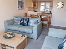A living room with a sofa and dining area at Daisy Lodge in Norwich