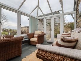 A conservatory with rattan chairs and glass doors at The Smithy in Blisland