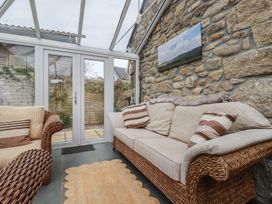 A conservatory with a sofa and rug at The Smithy in Blisland