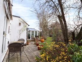 An outdoor patio with chairs tables potted plants and trees at The West Wing in Bodfari