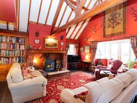 A living room with wooden beams a fireplace bookshelves sofas and red patterned carpet at The West Wing in Bodfari