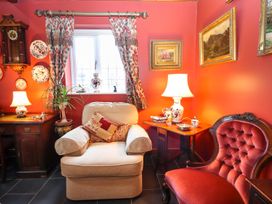 A sitting room with two armchairs a wooden side table with lamps and decorative plates on the wall at The West Wing in Bodfari
