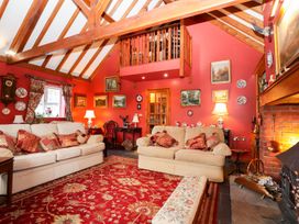 A living room with two beige sofas a red patterned rug and wooden beams at The West Wing in Bodfari