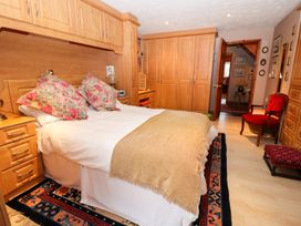 A bedroom with a double bed floral pillows wooden wardrobes and a red chair at The West Wing in Bodfari