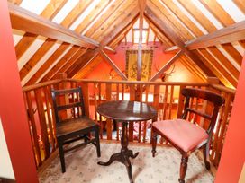 A loft area with a small round table and two chairs under a wooden beam ceiling at The West Wing in Bodfari