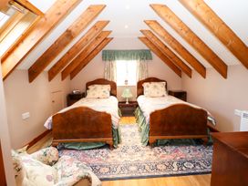 A bedroom with two single beds a floral armchair and wooden beams on the ceiling at The West Wing in Bodfari
