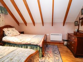 A bedroom with two single beds a wooden dresser a patterned rug and exposed ceiling beams at The West Wing in Bodfari