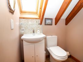 A bathroom with a white sink, toilet, a mirror, a small wall painting, and a skylight window at The West Wing in Bodfari