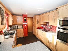 A kitchen with wooden cabinets and red tile backsplash at The West Wing in Bodfari