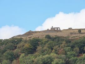 Ruins on a hilltop with trees below at Talgais Llangollen