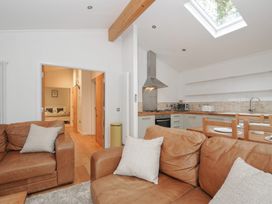 A living room with a sofa and kitchen area at 2 Streamside in Looe