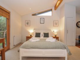 A bedroom with a bed, side tables and windows at 2 Streamside in Looe
