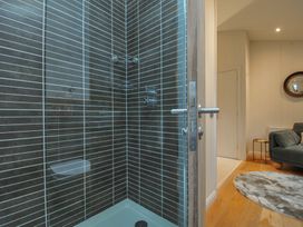 A shower with glass door and tiled wall at 2 Streamside Looe