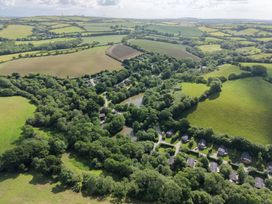 An aerial view of fields and a lake with houses at 6 Water's Edge in Lanreath