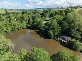 An aerial view of a lake surrounded by trees and cottages at 6 Water's Edge in Lanreath