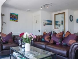 A living room with leather sofas and patterned cushions a glass coffee table with flowers and books a large mirror and wall art at Sea View apartment in Borth-Y-Gest