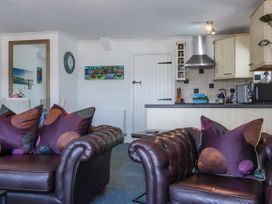 A living room with brown leather sofas and purple cushions next to a kitchen with beige cabinets at Sea View apartment in Borth-Y-Gest