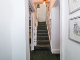 A hallway with carpeted stairs leading up and framed pictures on the wall at Sea View apartment in Borth-Y-Gest