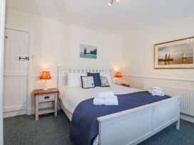 A bedroom with a white bed and blue bedding two bedside tables with lamps and framed pictures on the walls at Sea View apartment in Borth-Y-Gest