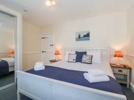 A bedroom with a white bed with folded towels on a blue cover and two bedside tables with lamps at Sea View apartment in Borth-Y-Gest