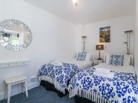 A bedroom with two single beds with blue and white patterned blankets and cushions a small white stool and a decorative wall mirror at Sea View apartment in Borth-Y-Gest