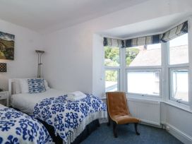 A bedroom with two single beds next to a window and a brown chair near the window in Sea View apartment in Borth-Y-Gest