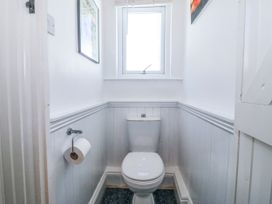 A small bathroom with a toilet under a window and a toilet paper holder on the left wall at Sea View apartment in Borth-Y-Gest