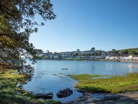 A waterfront view with houses on a hill across the water and trees on the left at Sea View apartment in Borth-Y-Gest