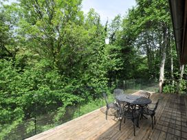 An outdoor area with a table and chairs overlooking trees at 14 Stonerush Valley Lanreath