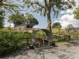 An outdoor area with a lodge and a circular bench at Meadow Retreat Nantmel near Rhayader