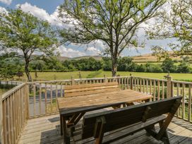 An outdoor seating area with a wooden table and benches at Meadow Retreat Nantmel near Rhayader