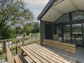 An outdoor area with wooden furniture and view of trees and road at Meadow Retreat in Nantmel near Rhayader