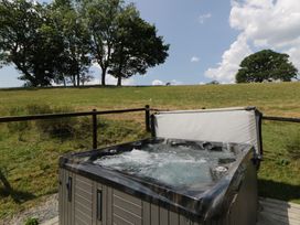 A hot tub with trees in the background at Meadow Retreat in Nantmel near Rhayader