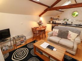 A living room with a sofa and dining area at Holemire Barn Lorton