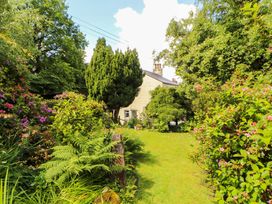 A garden with various plants and a house at Holemire Barn in Lorton