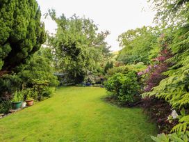A garden with trees, shrubs, and a garden bench at Holemire Barn in Lorton
