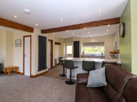 A living room with a kitchen counter and bar stools at Dalar Deg in Aberdaron