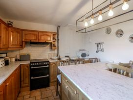 A kitchen with cabinets, stove, microwave, and table at Cairbre House, Dungarvan, County Waterford